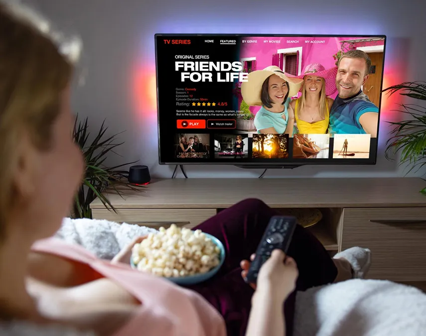 A woman with popcorn watching a series on a wall-mounted TV